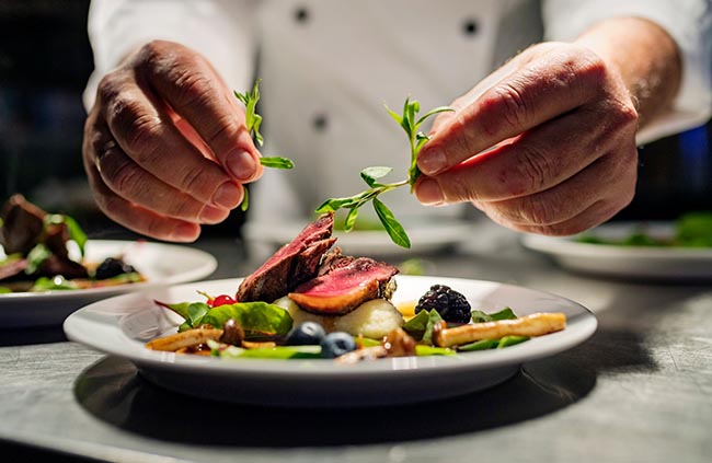 Chef adding garnish to a plate of food
