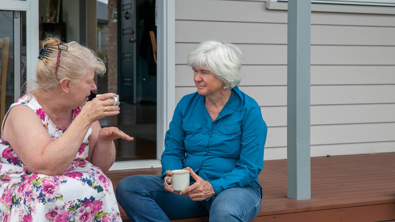 Two older women enjoying a cup of tea on the porch