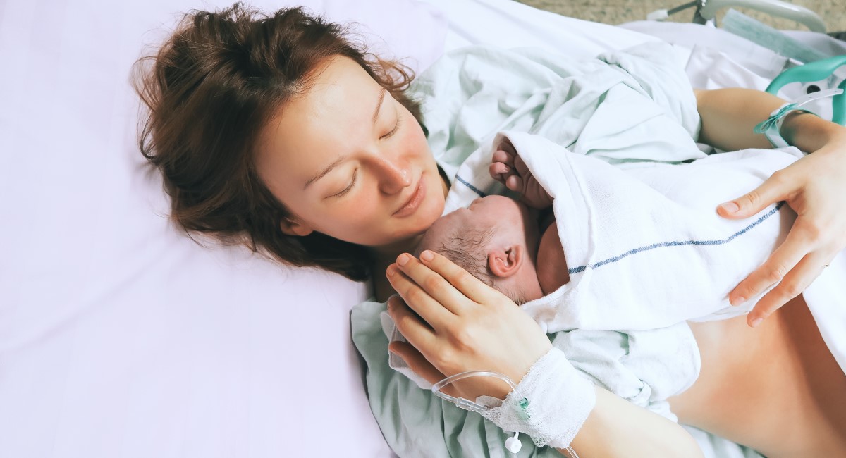 Mother holding newborn baby in hospital bed