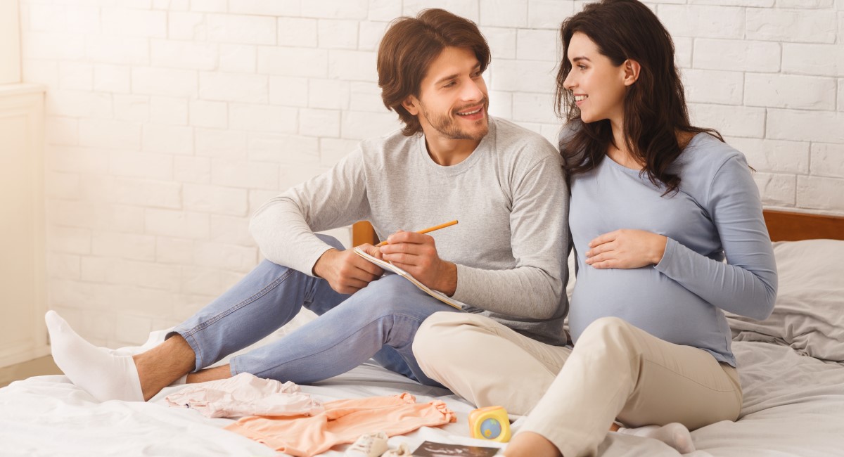 Pregnant woman and partner smiling and making plans