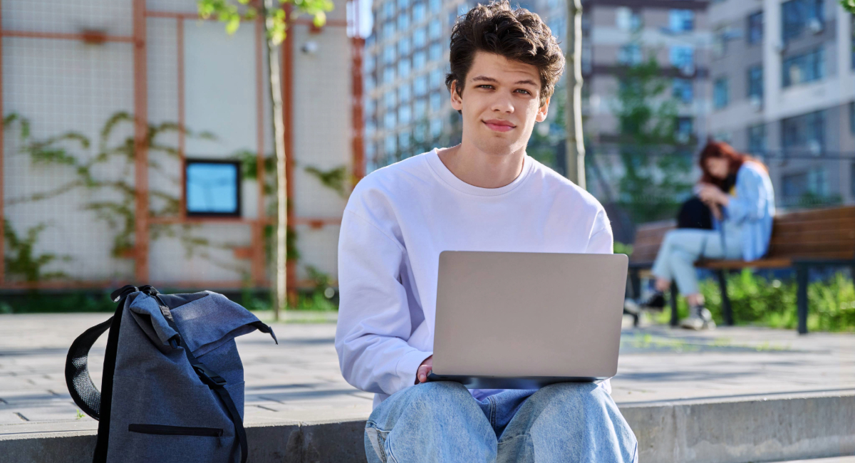 A young man smiling at the camera on his laptop