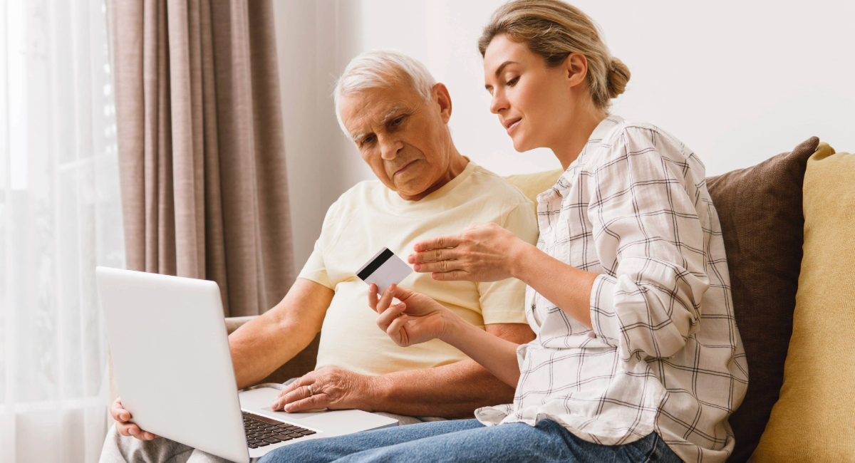 A women with an elderly man looking at a bank card