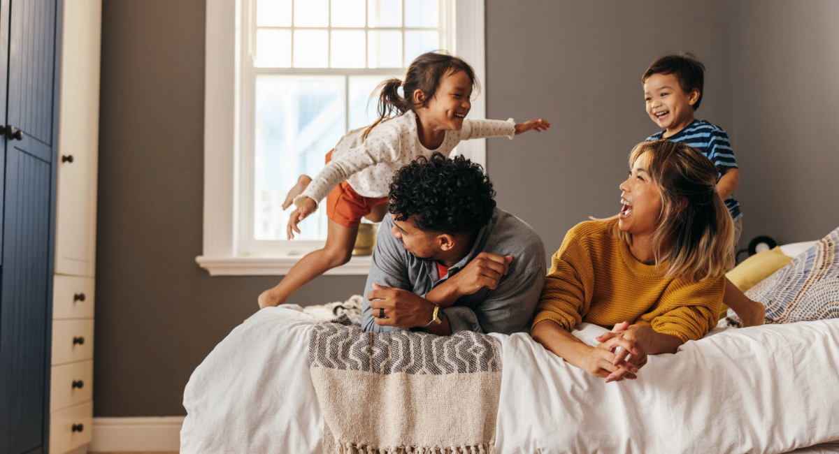 A young family of four having fun on a bed