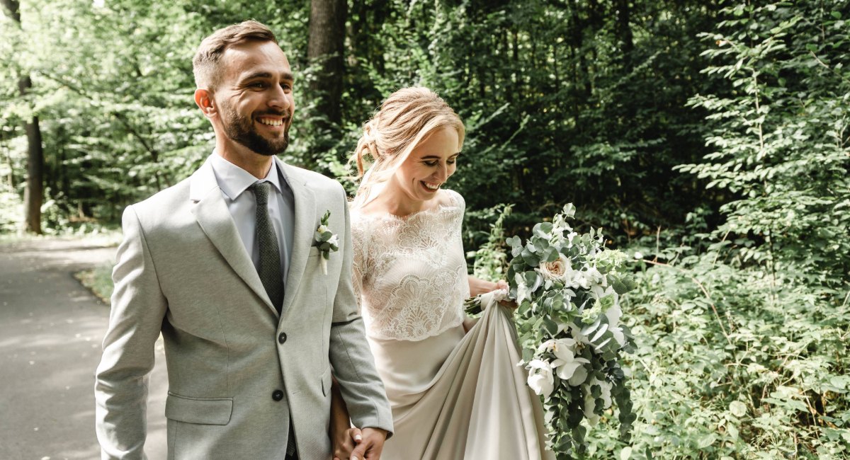 Newlyweds holding hands and walking through a park