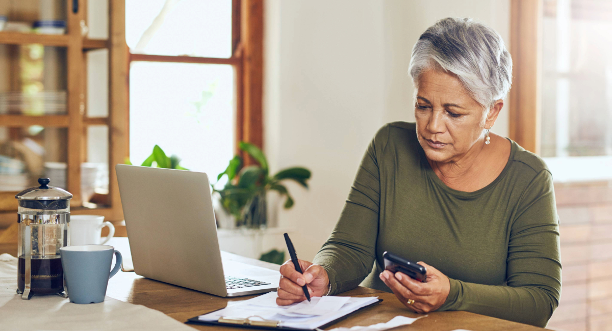 An older woman doing paperwork with a laptop in front of her