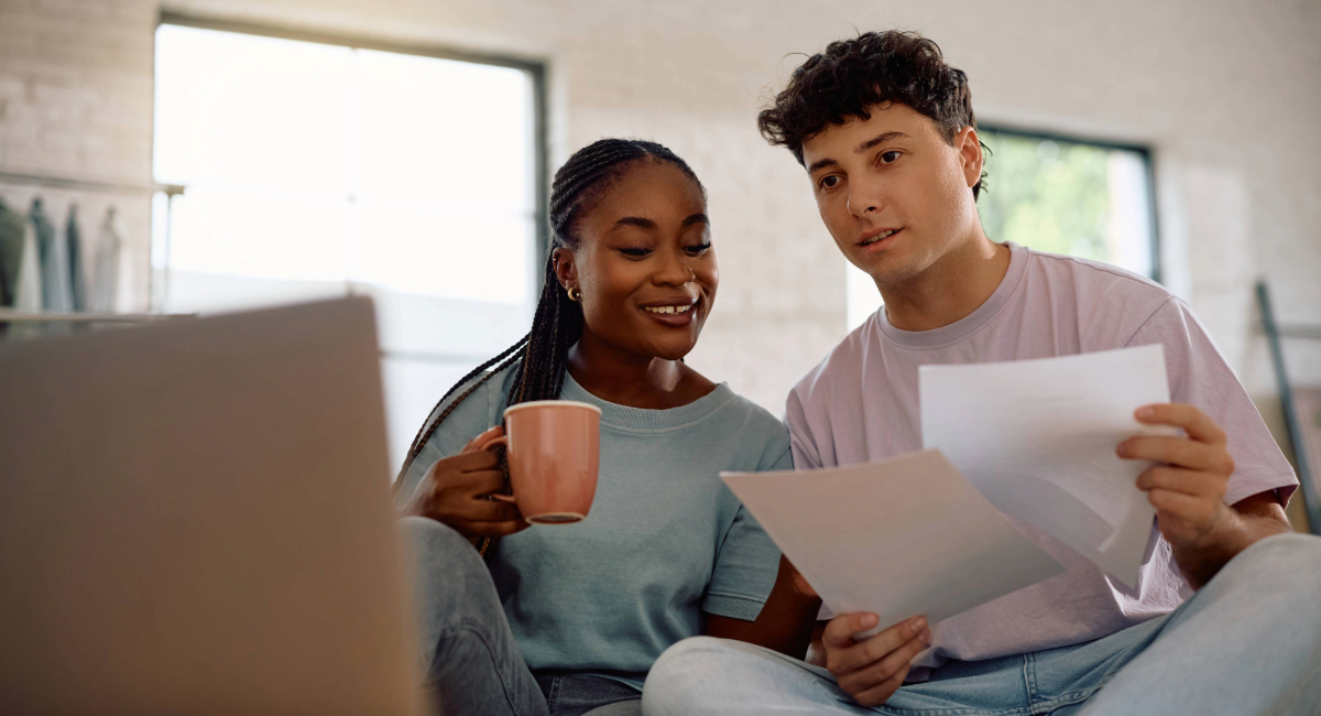 A young couple looking at paperwork with a laptop in front of them